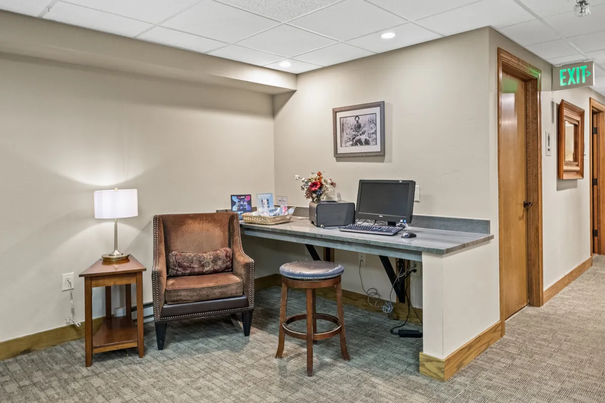 A comfortable nook with a chair and table, paired with a computer workstation and decorative artwork, providing a casual yet functional space for working remotely or planning local excursions.